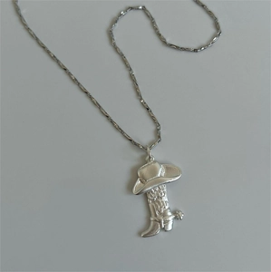 Détail macro d'un pendentif chapeau et botte de cowboy avec motifs en relief
