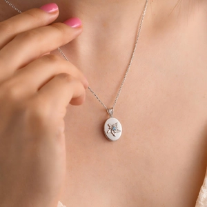 Dettaglio della collana a medaglione ovale in argento con rilievo floreale e gemma blu