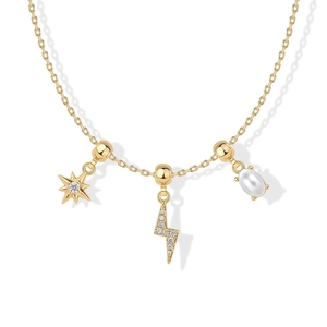 Detail van gouden ketting met ster-, bliksem- en parelhangers met zirkonia inleg