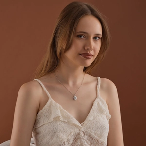 Collana con medaglione d'argento vintage e incisione floreale su modella con pizzo