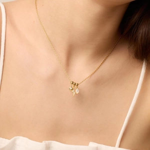 Gouden ketting met hanger van ster, bliksem en witte opaal gedragen door een model