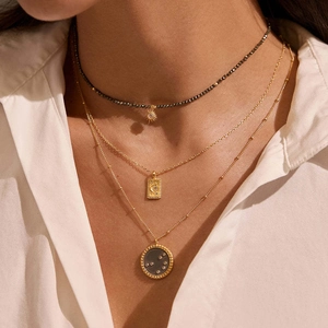 Detail of layered gold necklaces with sun moon and celestial pendants on model