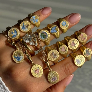 Detail view of retro gold signet rings with colorful enamel painting worn on hand