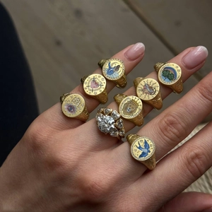 Close-up of stacked gold vintage rings with enamel lion and heart motifs and a diamond ring