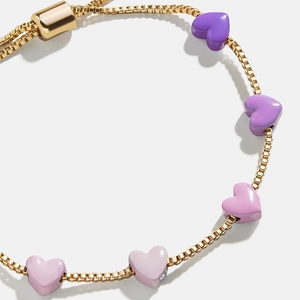Primer plano de dijes de corazón en degradado en pulsera de cadena dorada ajustable