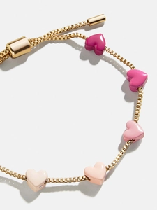 Detalle de pulsera de cadena dorada con cinco corazones de esmalte rosa y cierre ajustable