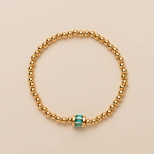 Detailed top view of a gold beaded bracelet featuring a single green rectangular gemstone