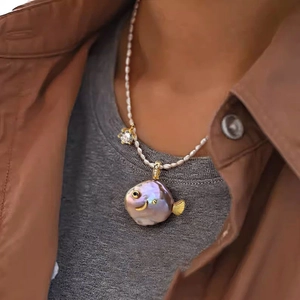 Baroque pearl fish necklace with gold details and zircon accents on a pearl string