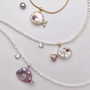 Macro detail of fish-shaped baroque pearl pendants with zircon inlays and colorful gems