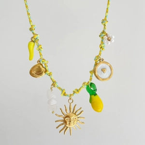 Dettaglio della collana intrecciata colorata con ciondoli a sole, conchiglia e limone