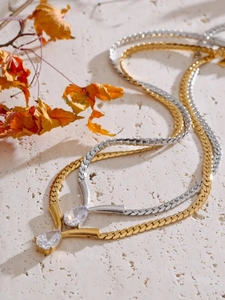Detailed view of gold and silver snake chains with pear-cut cubic zirconia pendants