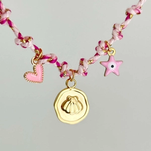 Vista macro di una collana boho in corda rosa intrecciata con ciondoli a cuore