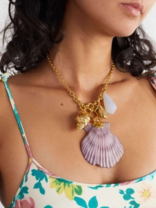 Close-up of a gold chain necklace with purple shell and sea charms on a model