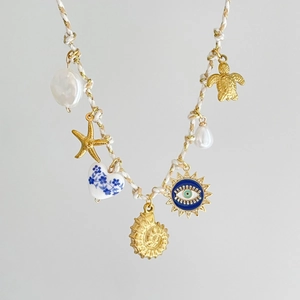 Dettaglio della collana in corda colorata con ciondoli a tartaruga marina e occhio