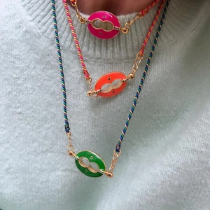 Detalle de collares de cuerda trenzada con colgantes de esmalte coloridos en una modelo