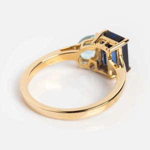 Nahaufnahme eines goldenen Rings mit saphirblauem Edelstein und hellblauen Akzenten