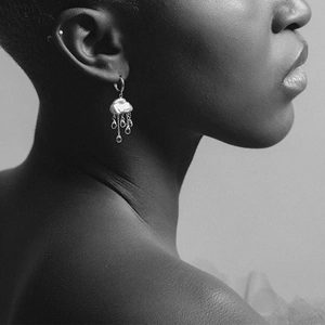 Foto artistica monocromatica di orecchini a nuvola e goccia di perla indossati da modella
