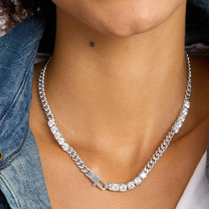 Detailed close-up of a silver-toned Cuban link and pave zircon tennis chain on a neck