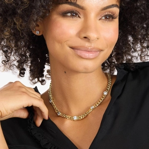 Close-up of gold Cuban link necklace with five large round cubic zirconia on model