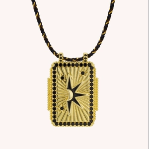 Detail of a rectangular gold tarot pendant with celestial sun-moon motif and black stones