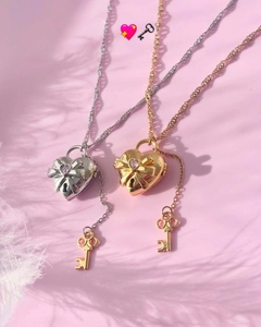 Detalle de collares con relicario de corazón y lazo en acabados oro y plata