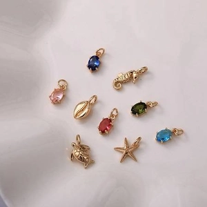 Detalle de colgantes marinos dorados con piedras de circonita ovaladas de colores