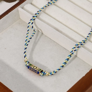 Close-up of bohemian woven bracelet with gold AMOUR enamel plate and colorful cords