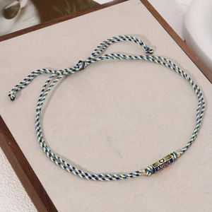Detail of hand-woven colorful silk rope bracelet with gold AMOUR engraved pendant