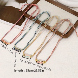 Detail of colorful woven cord bracelet set with gold accents and enamel charm beads