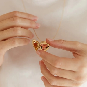 Détail d'un médaillon cœur doré ouvrant révélant une délicate fleur rose à l'intérieur