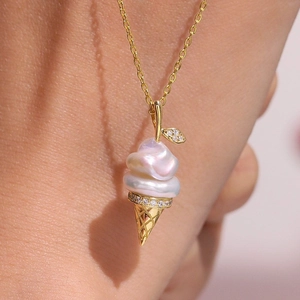 Macro detail of baroque pearl ice cream pendant with golden cone and sparkling zircons