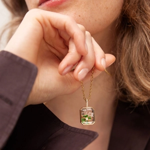 Gros plan d'un médaillon en verre doré 18 carats avec texte Luck et trèfle vert porte-bonheur