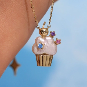 Macro shot of cupcake pendant necklace featuring a pink pearl and colorful star gems