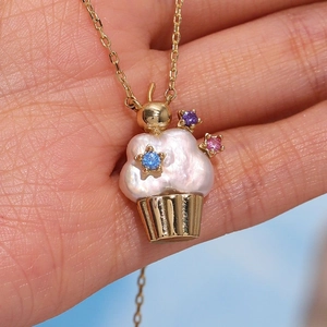 Close-up of pearl cupcake pendant necklace with colorful gemstones and gold accents
