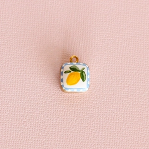 Square lemon pendant necklace with blue polka dot border on pink background