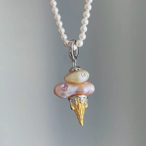 Macro detail of ice cream pendant with baroque pearls and pink heart gemstone charm