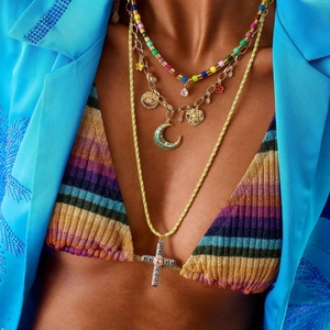Gros plan de colliers bohèmes superposés avec perles colorées et pendentif croix sur un mannequin
