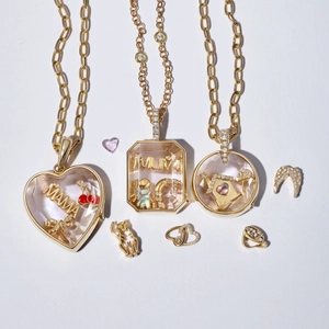 Flat lay of 18k gold-plated lockets with interchangeable charms and MAMA lettering