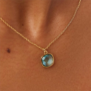 Primer plano del collar de oro con un colgante cuadrado de piedra preciosa verde oliva