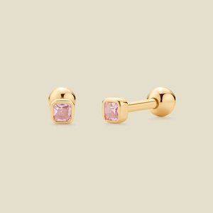 Macro shot of gold stud earring with square pink zircon and polished finish