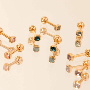 Detailed macro view of gold screw-back earrings with square multi-color zircon stones