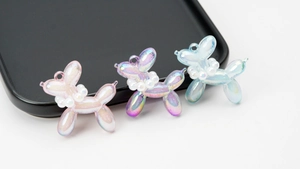 Macro detail of pearlescent balloon dog charms with pearl collars for DIY accessories