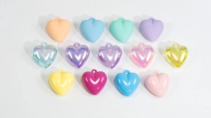 Macro shot of 13 colorful acrylic heart pendants in matte, aurora, and glossy finishes