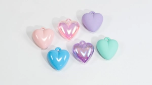 Macro detail of mixed acrylic heart charms in matte, glossy, and iridescent finishes