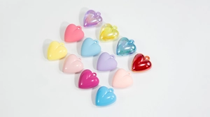 Close-up of 12 colorful acrylic heart pendants in matte and glitter for DIY crafts