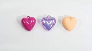 Three colorful acrylic heart pendants in glossy pink, iridescent purple, and matte orange