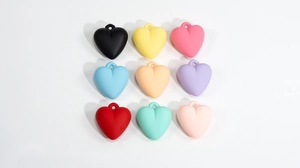 Macro detail of nine colorful matte acrylic heart charms with hanging loops for DIY