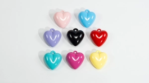 Macro detail of glossy acrylic heart pendants in eight vibrant colors for DIY accessories