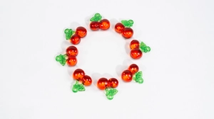 Detailed view of eight transparent red cherry pendants with green leaves for DIY jewelry