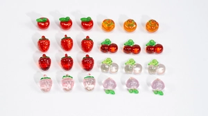 Macro detail of translucent fruit charms like strawberry and apple for DIY jewelry making